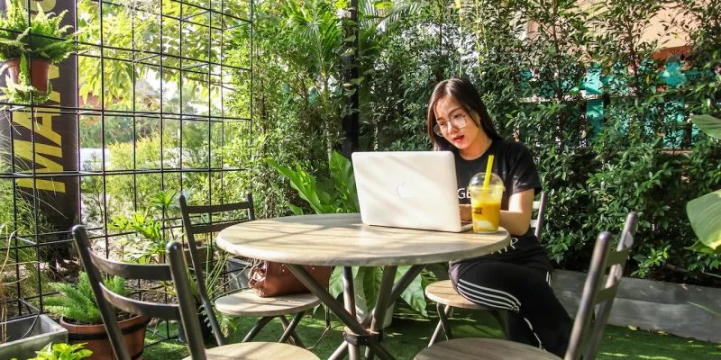 digital nomad working on her laptop outside in a tropical setting